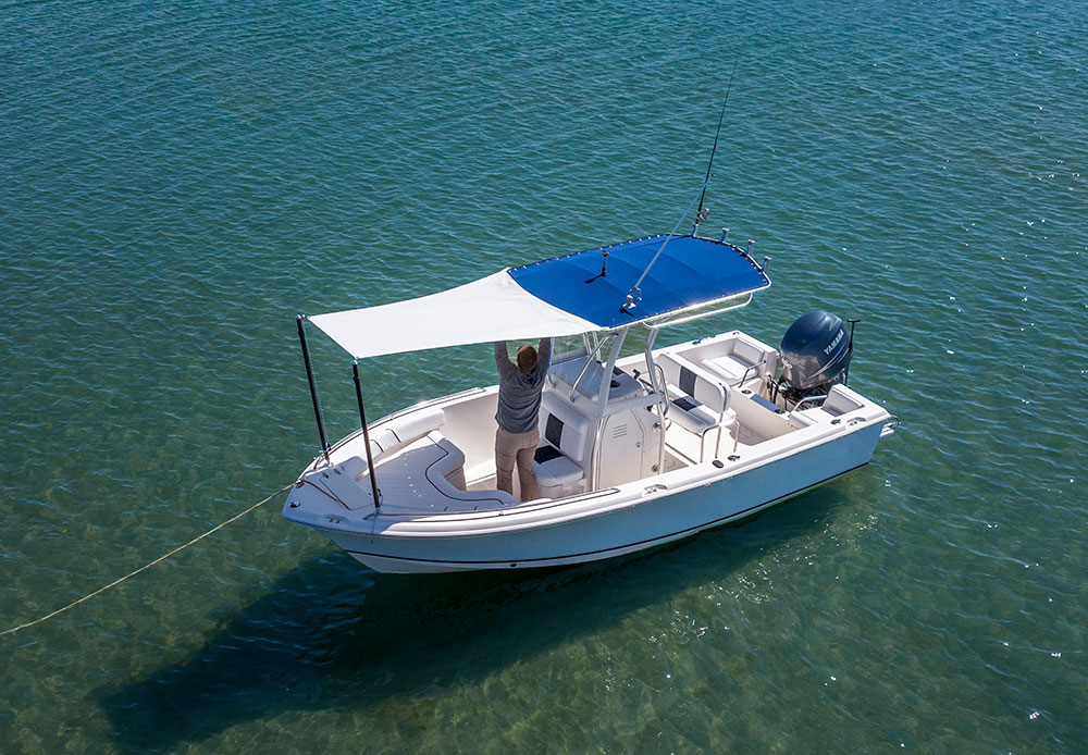 Top view of a yacht on the water with a man adjusting a sunshade
