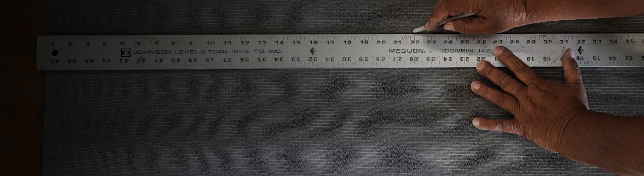 A person's hands measuring fabric with a measuring stick