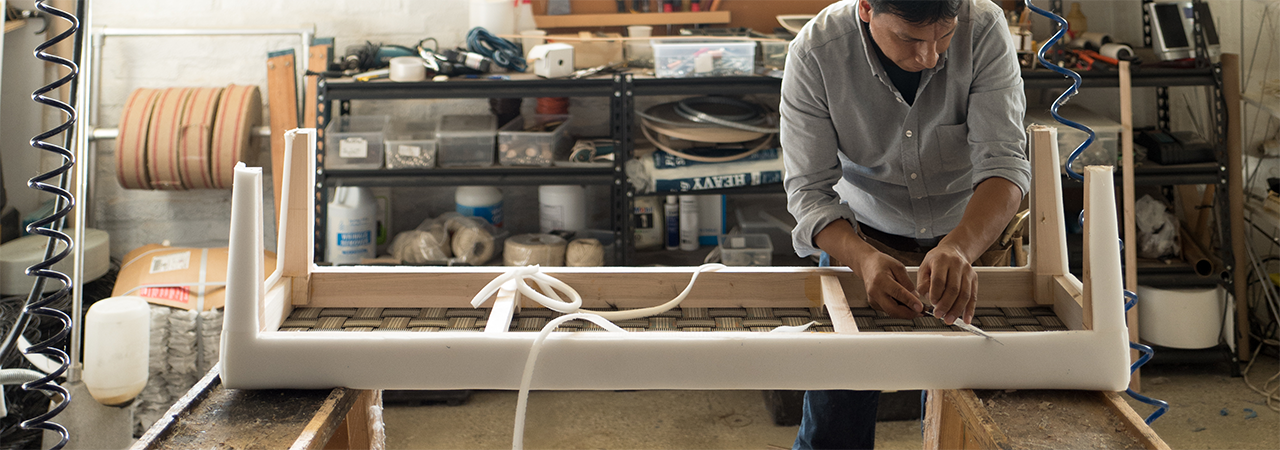 Banner image for the become a customer page showing a fabricator working on an upholstered bench.