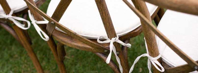Dark wooden dining chairs featuring white upholstery cushions made with white cotton tie backs fabricated from non-adhesive fabric tape.