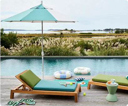 Image of outdoor lounge furniture with blue and green cushions at a pool side.