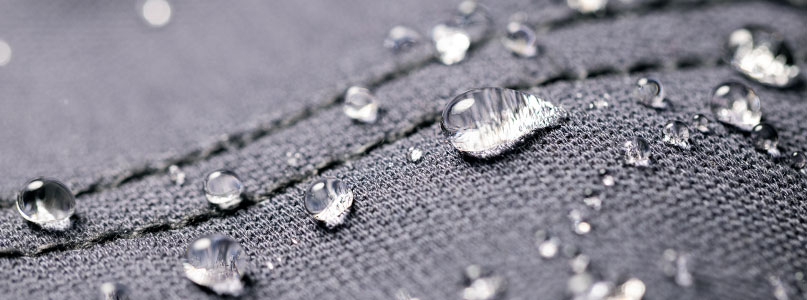 Image of waterproof fabric with water beads featuring a seam sewn with seam tape to improve water resistance.