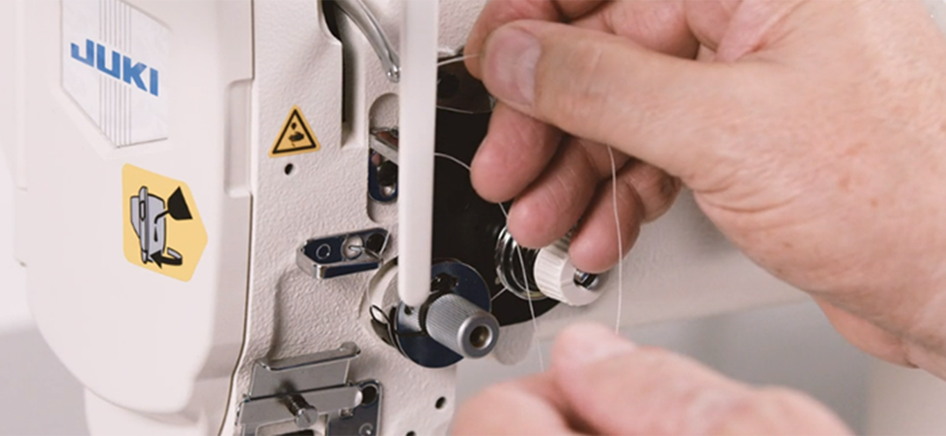 masculine hands threading white juki industrial sewing machine