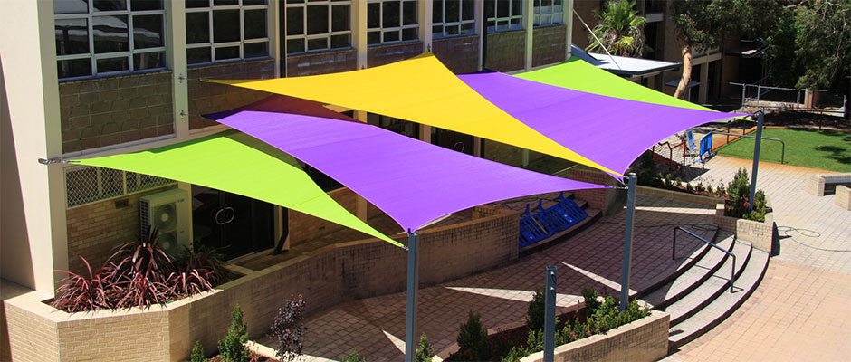 outdoor tension shade sail installation of purple, yellow, and green polytex fabric